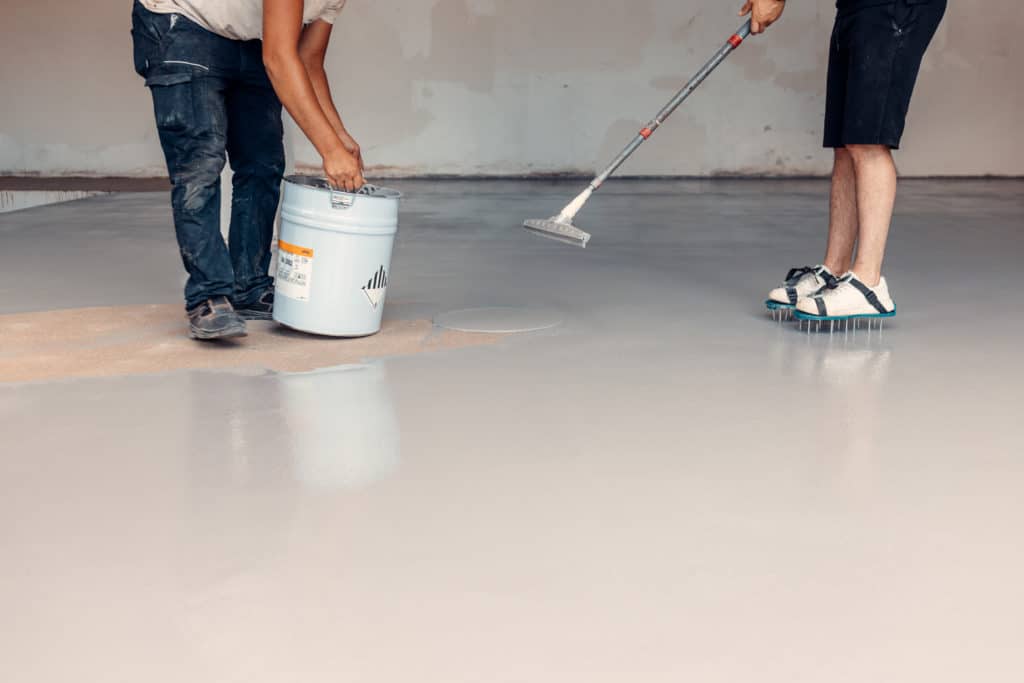 Applying epoxy floor coating in an industrial space.