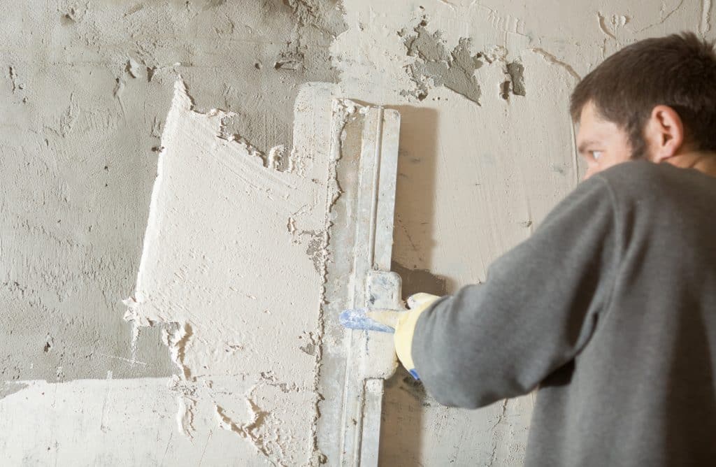 Worker applying plaster to wall with trowel.