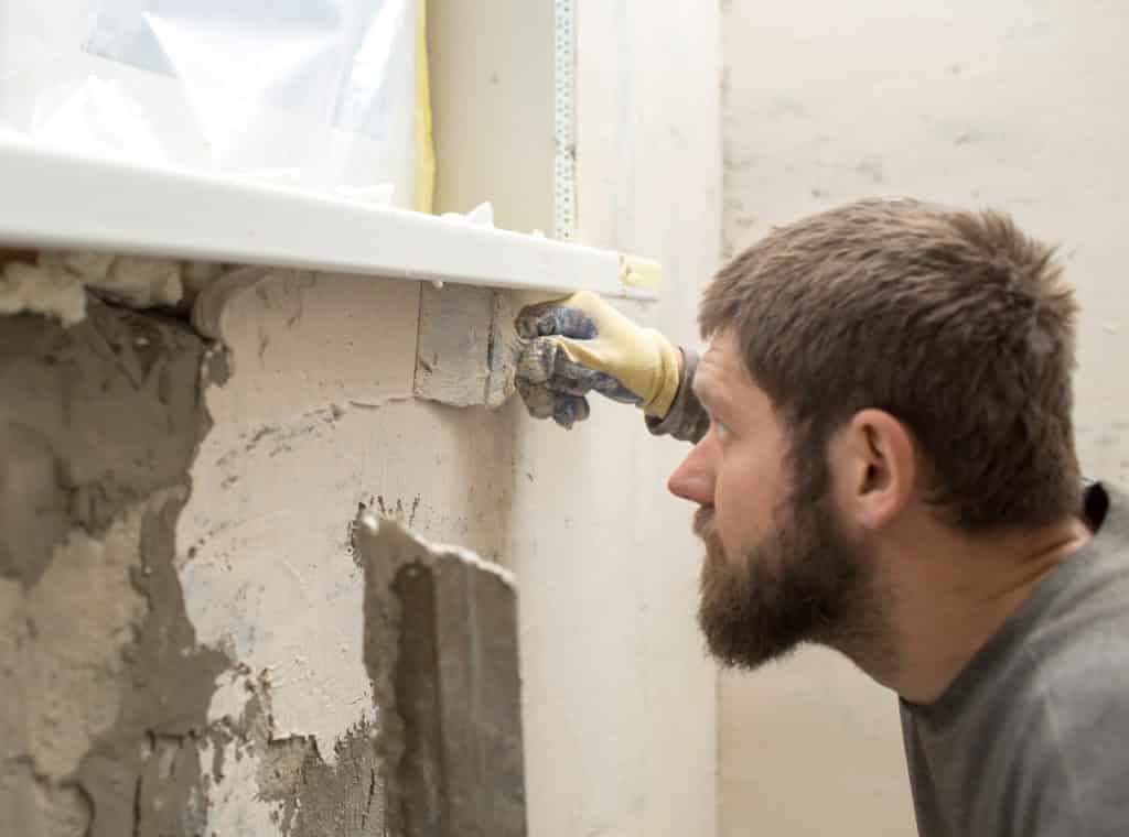 Man applying plaster to wall, construction detail.