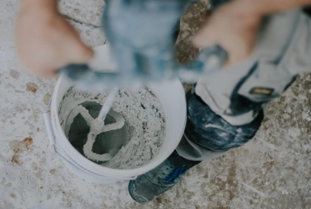 Worker mixing concrete with electric drill