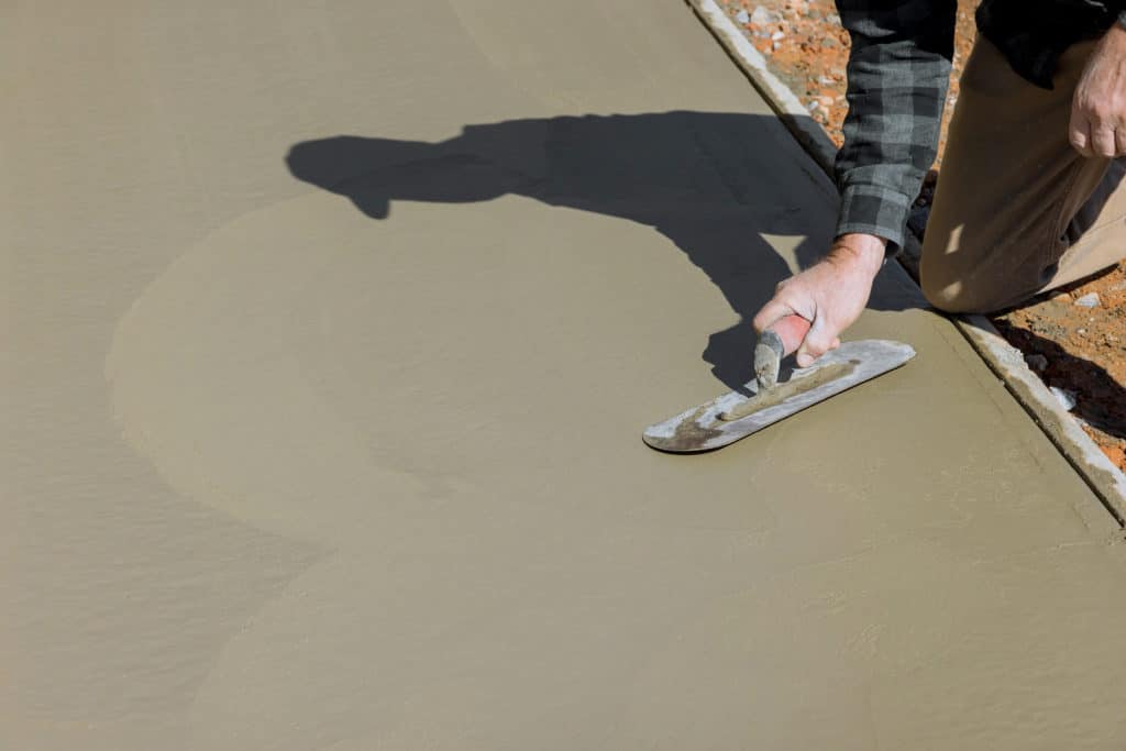 Worker smoothing concrete with trowel.