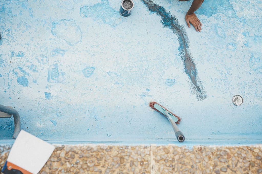 Person repairing blue peeling paint surface.