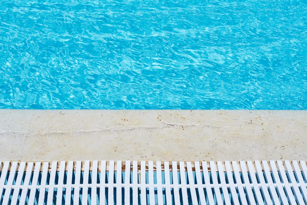 Swimming pool edge with water and drain grille.