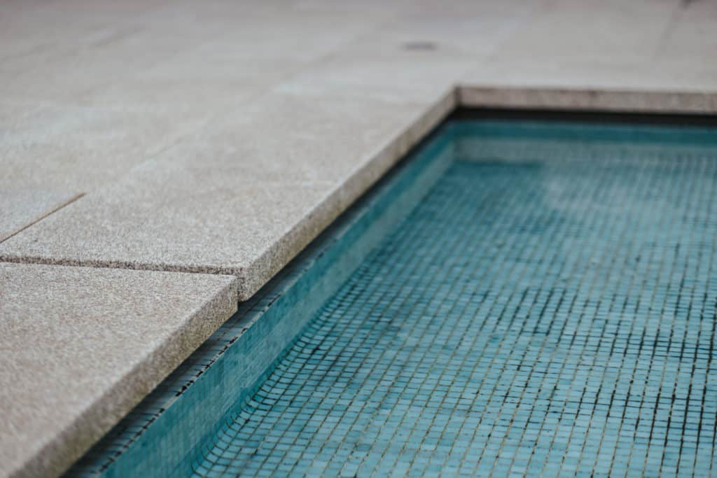 Close-up of pool edge with blue mosaic tiles.