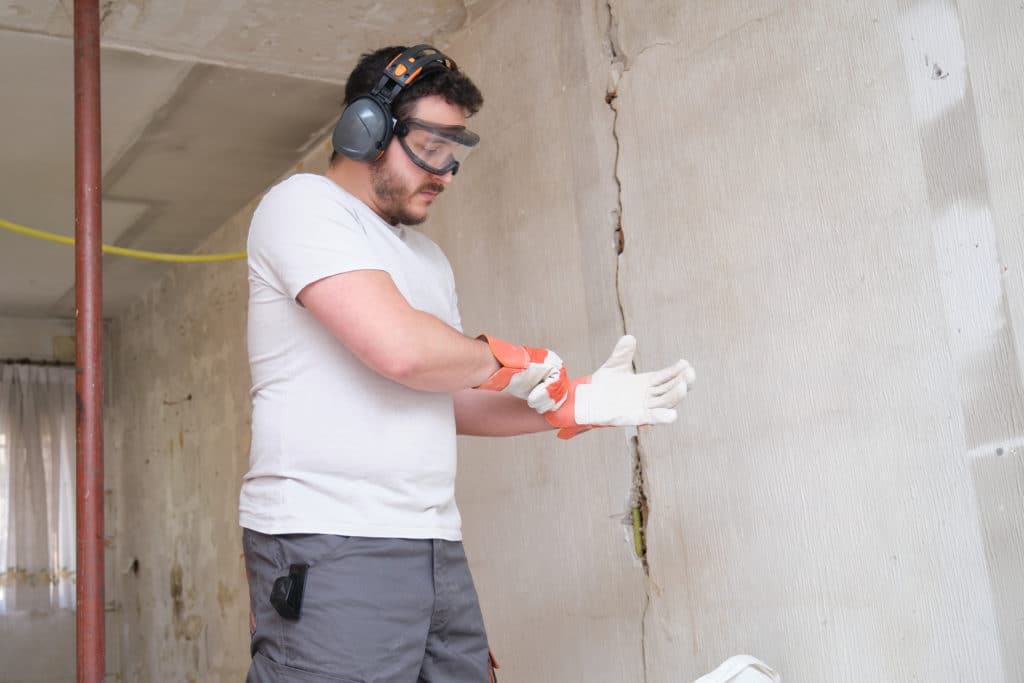 Worker inspecting a cracked concrete wall.