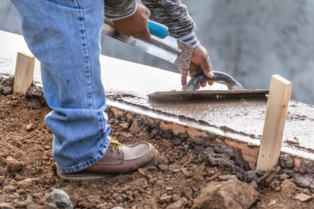 Worker smoothing concrete with trowel.