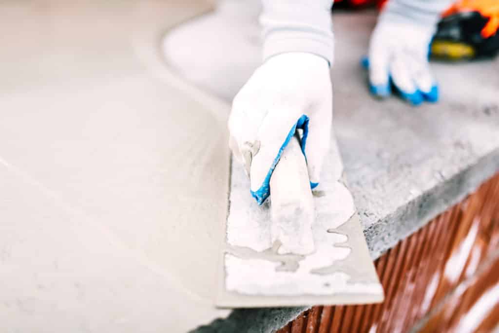 Worker applying cement with trowel.