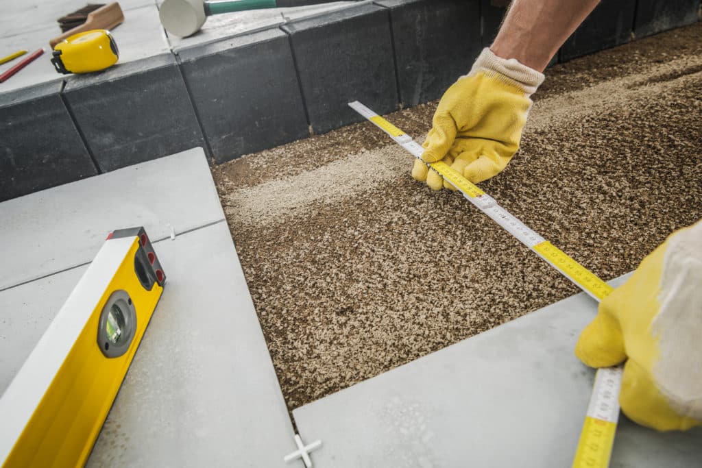 Worker measuring for patio tile installation