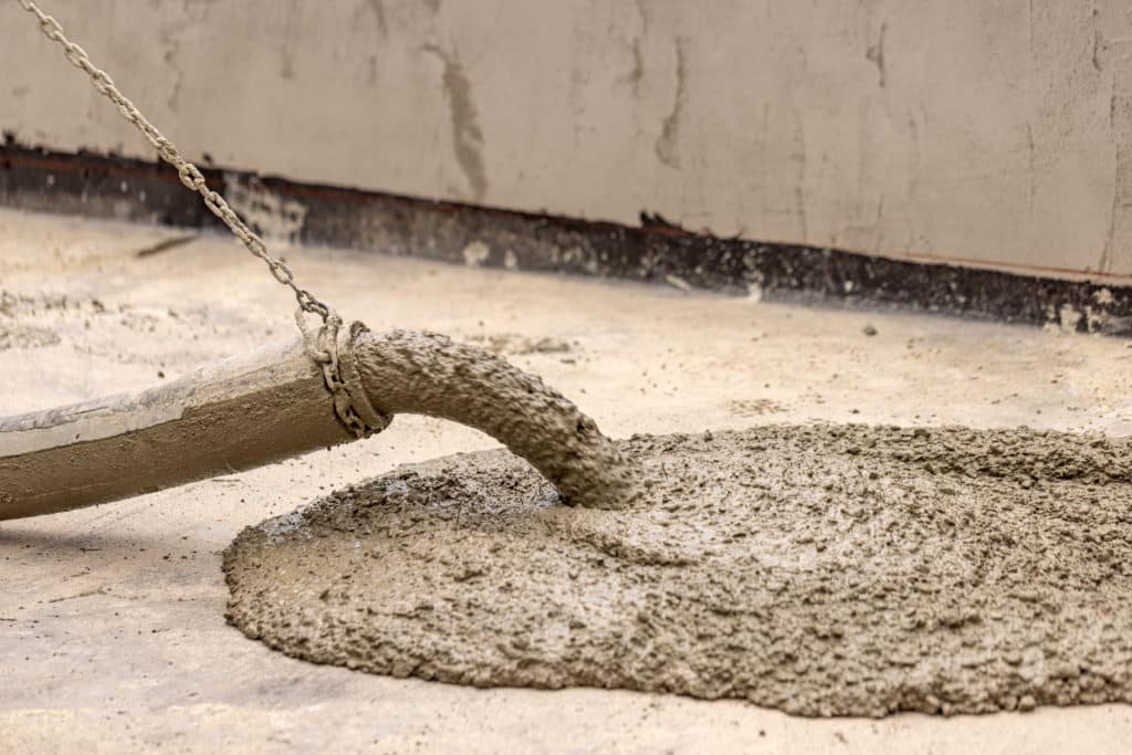 Pouring concrete with a hose at construction site.