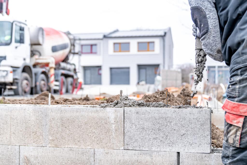 Construction worker laying concrete blocks on site.