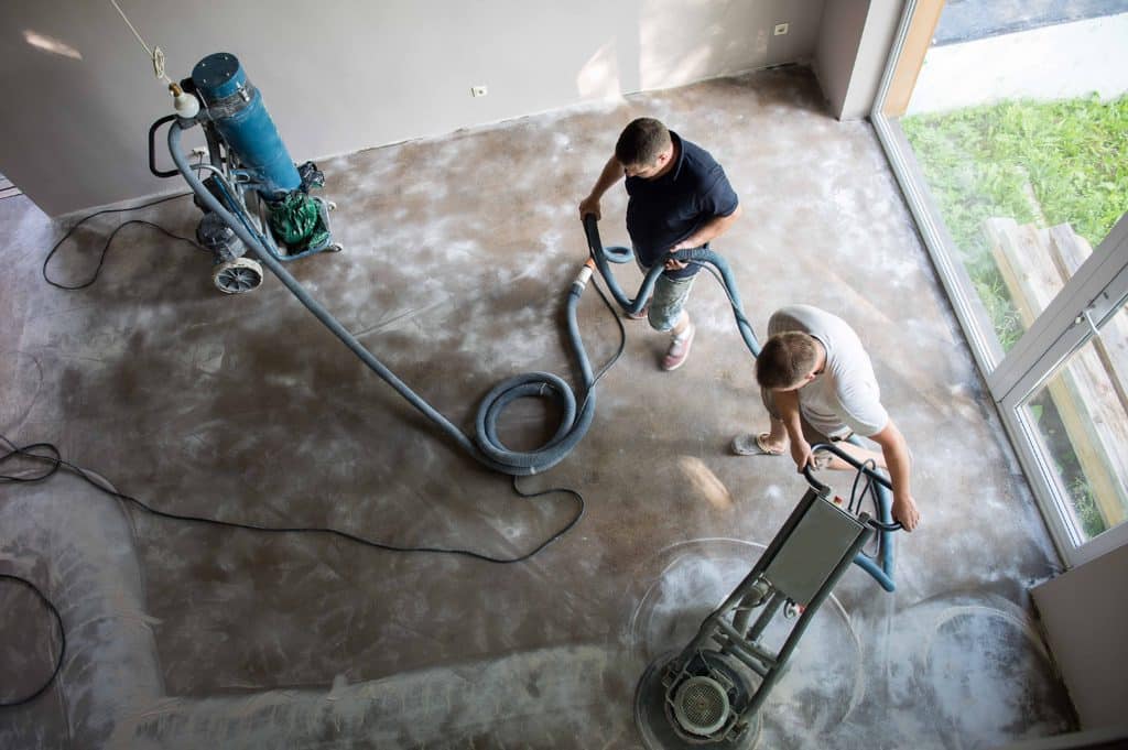 Workers polishing concrete floor indoors.