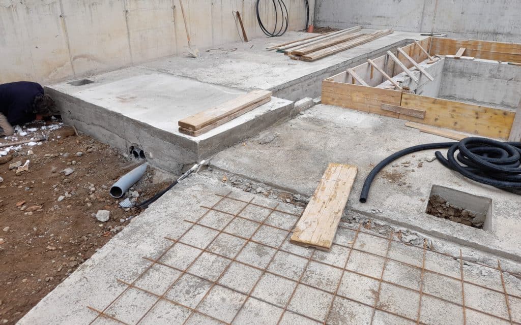 Construction site with concrete foundations and rebar grid.