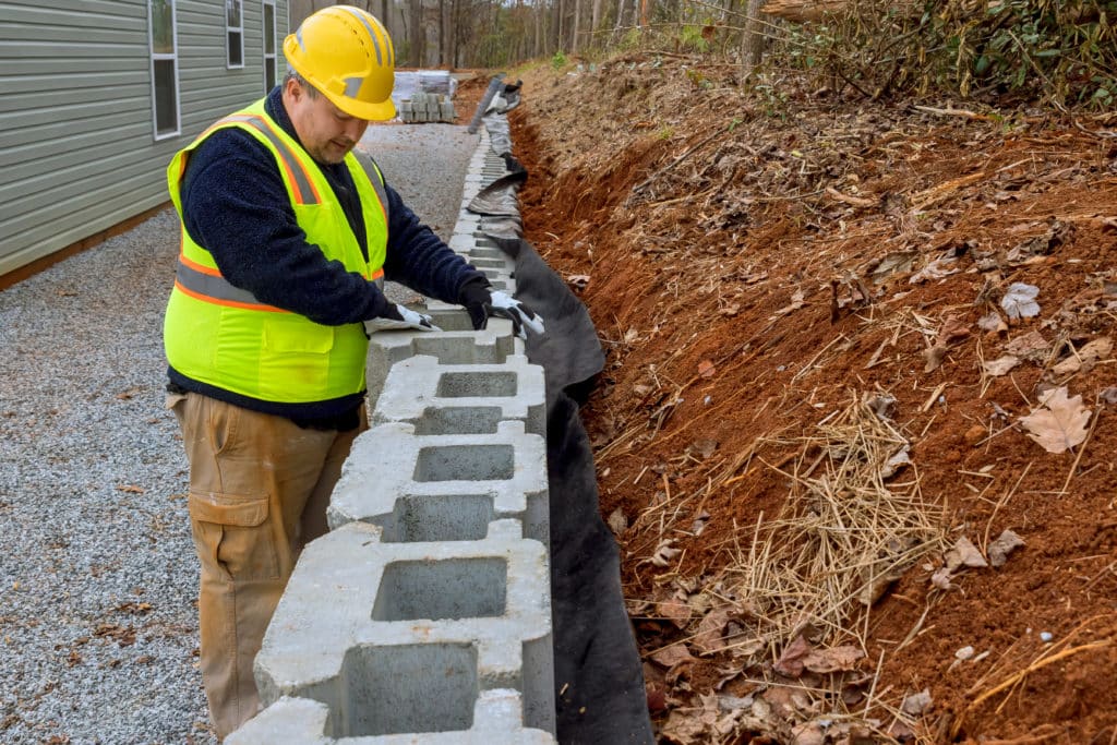 Construction worker laying concrete blocks for retaining wall.