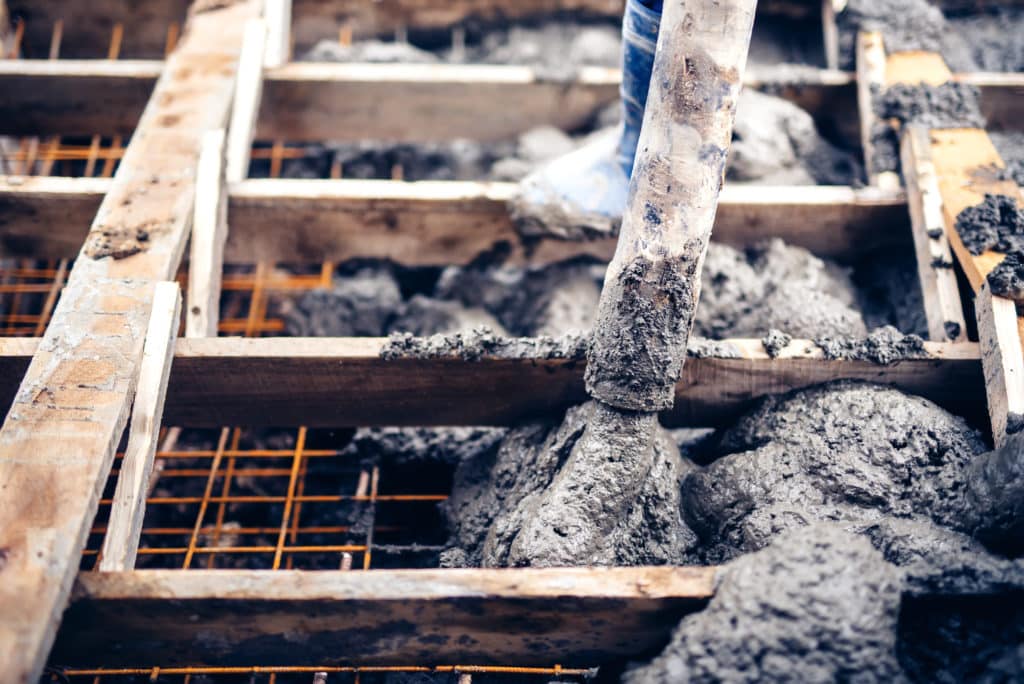 Concrete pouring into foundation forms at construction site.