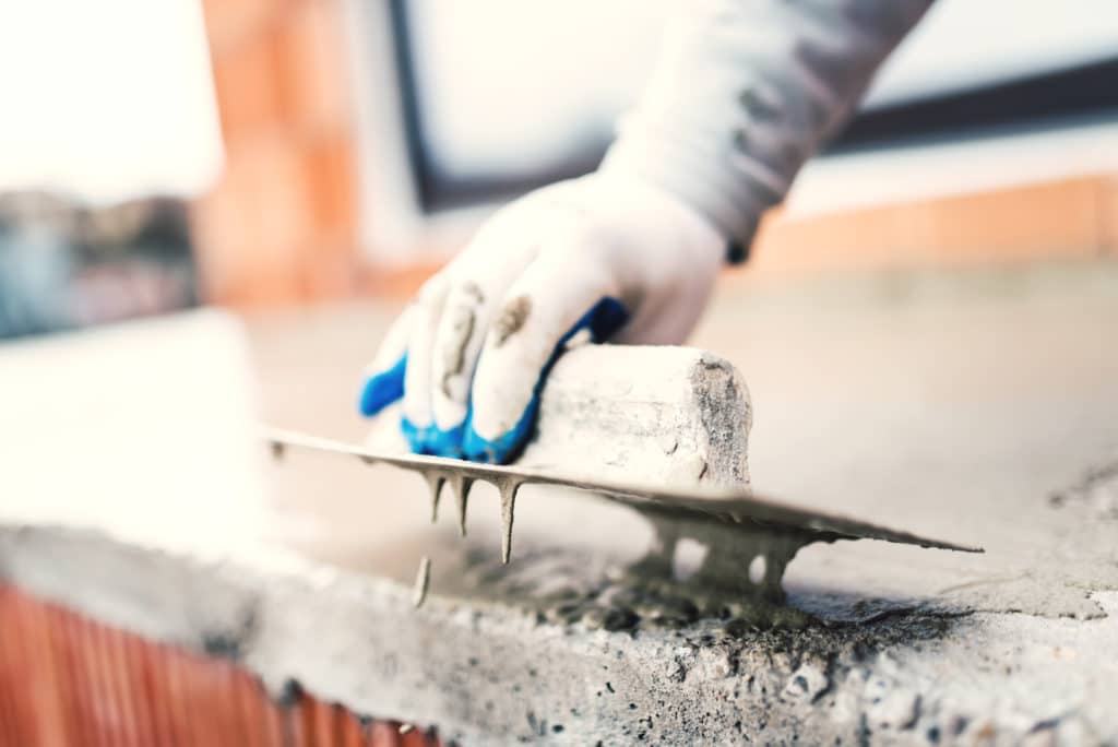 Worker smoothing concrete with trowel.