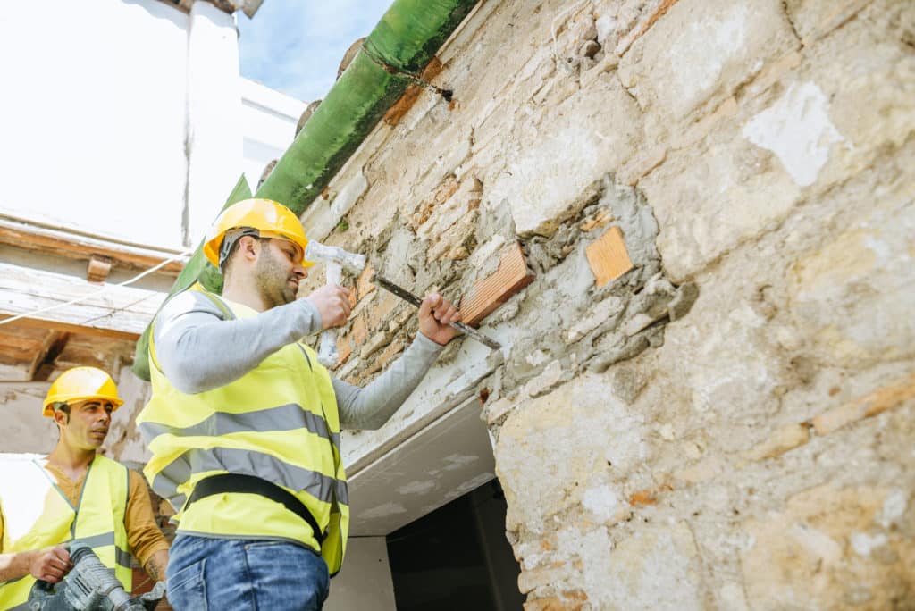 Construction workers repairing a brick wall.