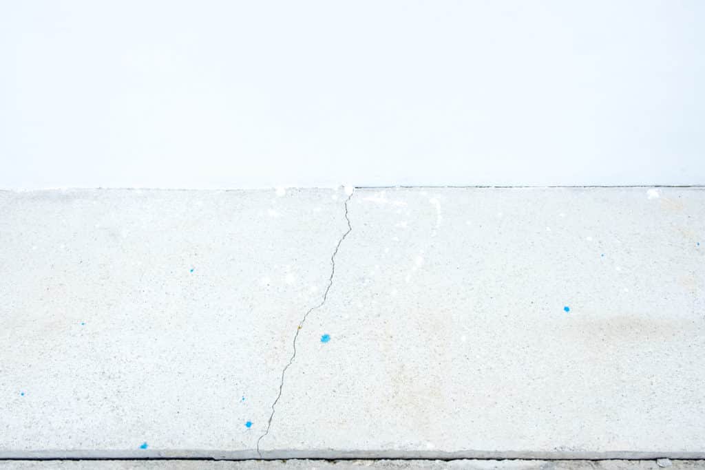 Concrete surface with hairline crack and blue specks