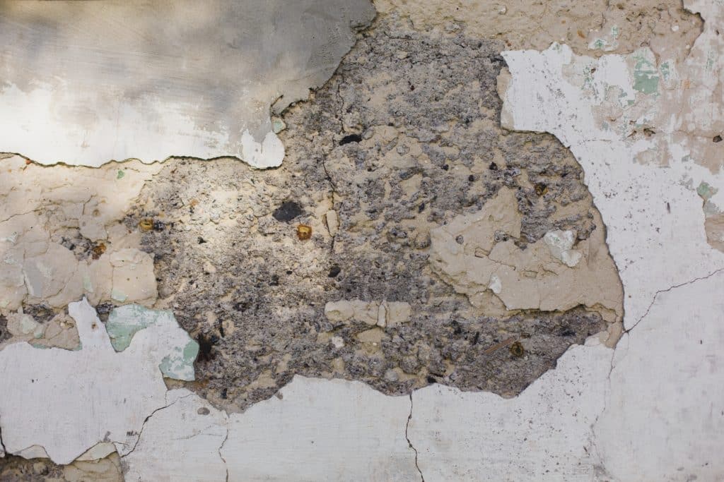 Peeling paint on deteriorating concrete wall