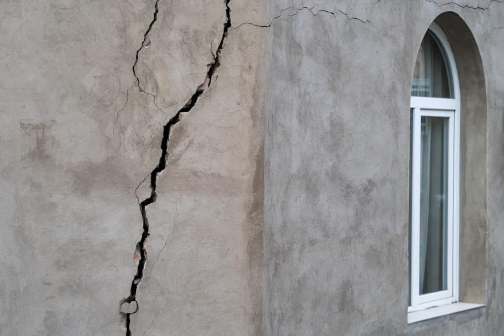 Cracked building exterior wall with arched window.