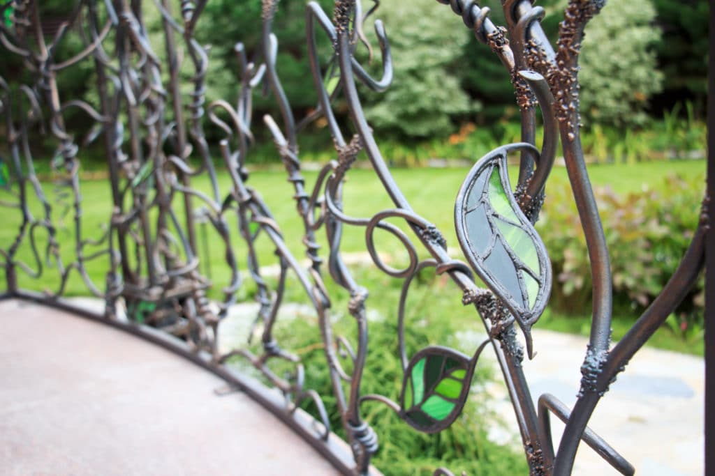 Decorative wrought iron fence with glass details in garden.