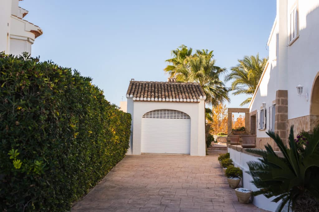 Mediterranean home driveway with white garage door.