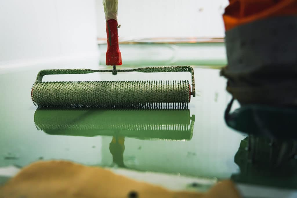 Paint roller with reflection on glass surface.