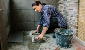 Woman installing tiles on a floor.