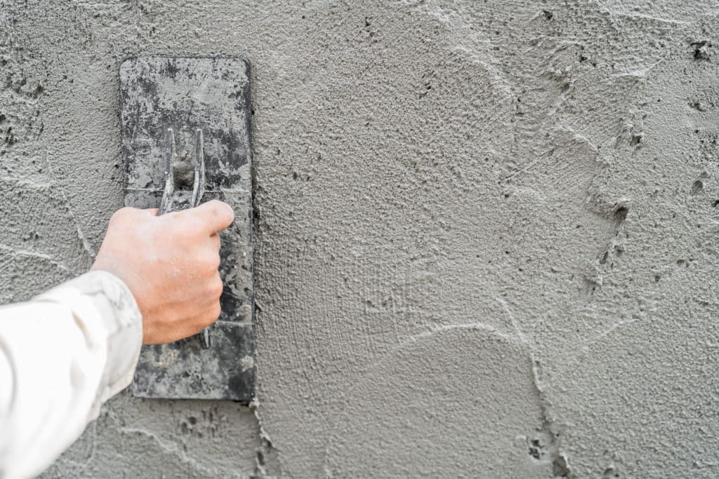 Hand plastering concrete wall with trowel.