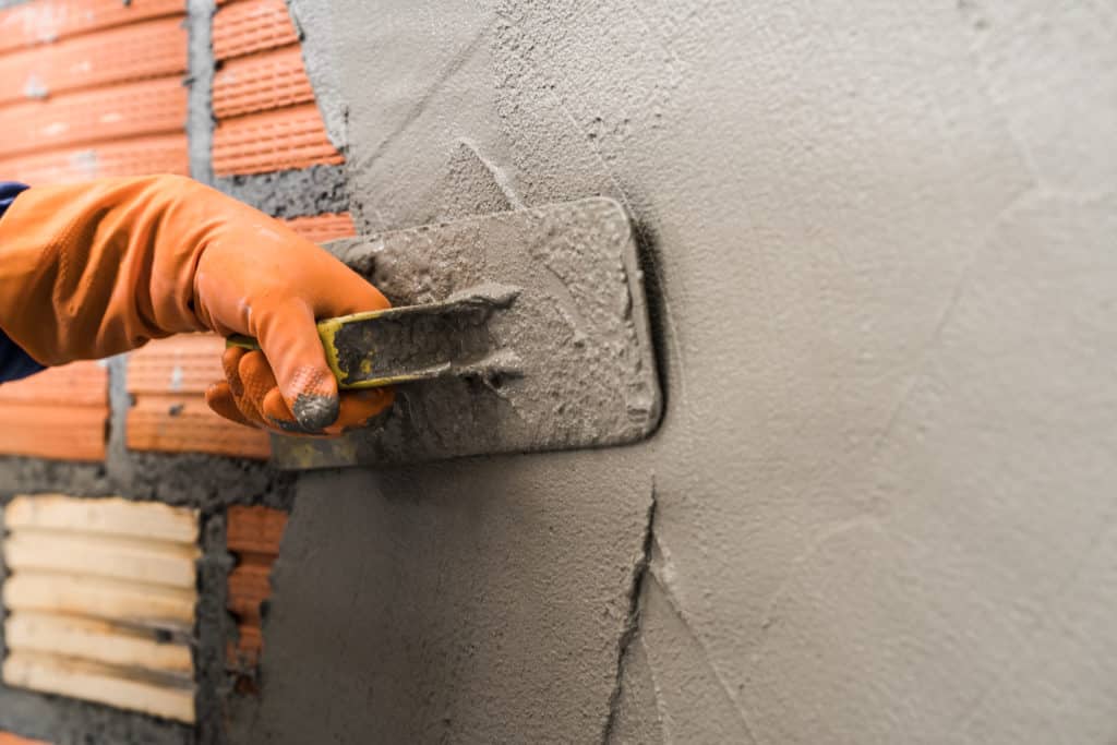 Worker applying plaster on wall with trowel.