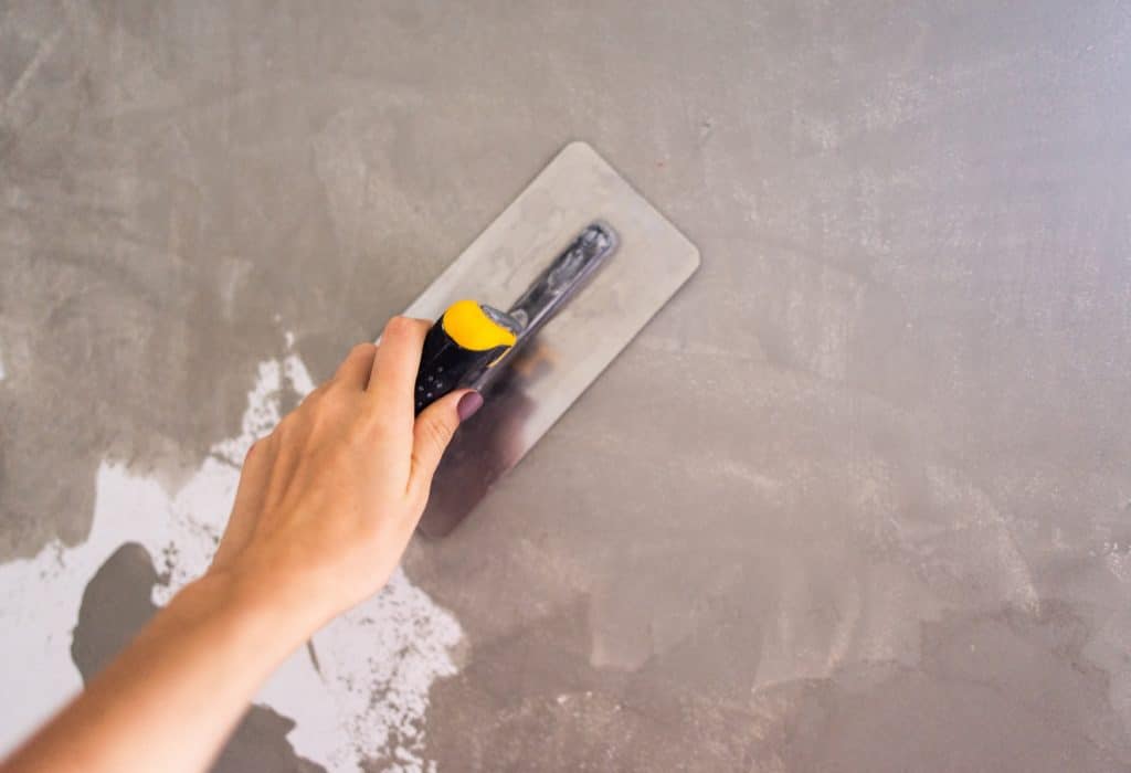 Person plastering wall with finishing trowel.