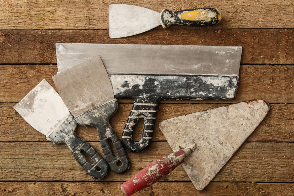 Assorted used plastering trowels on wooden surface