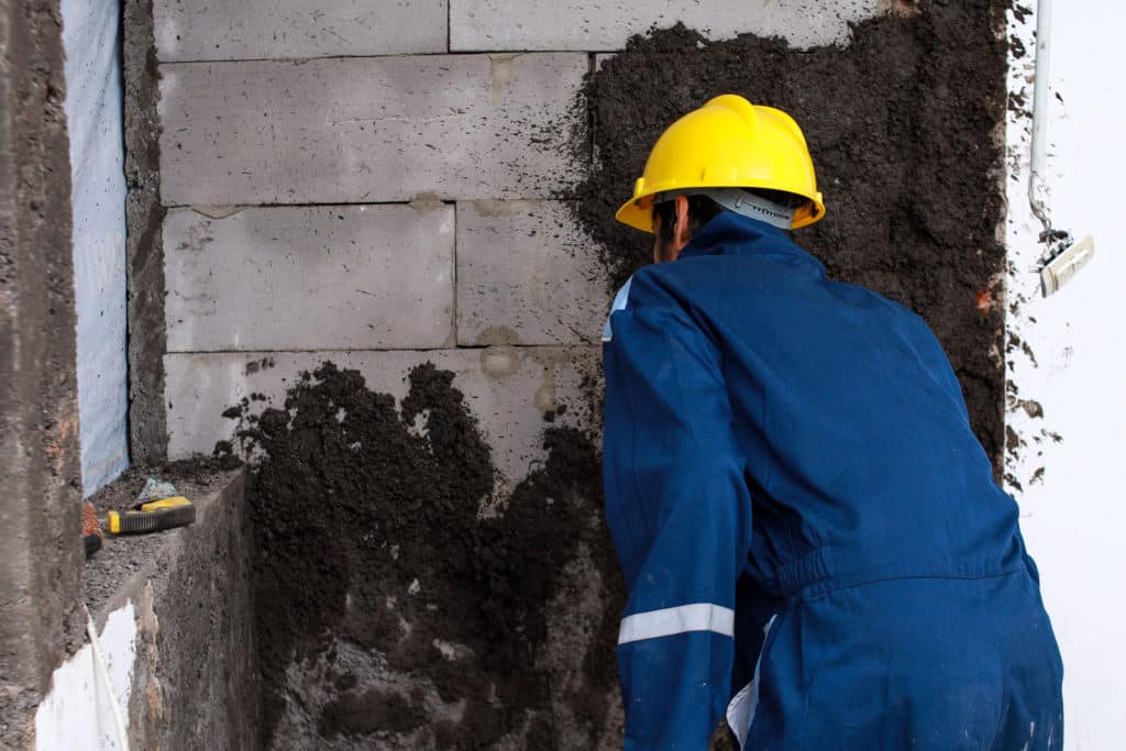 Worker in hard hat plastering a wall.