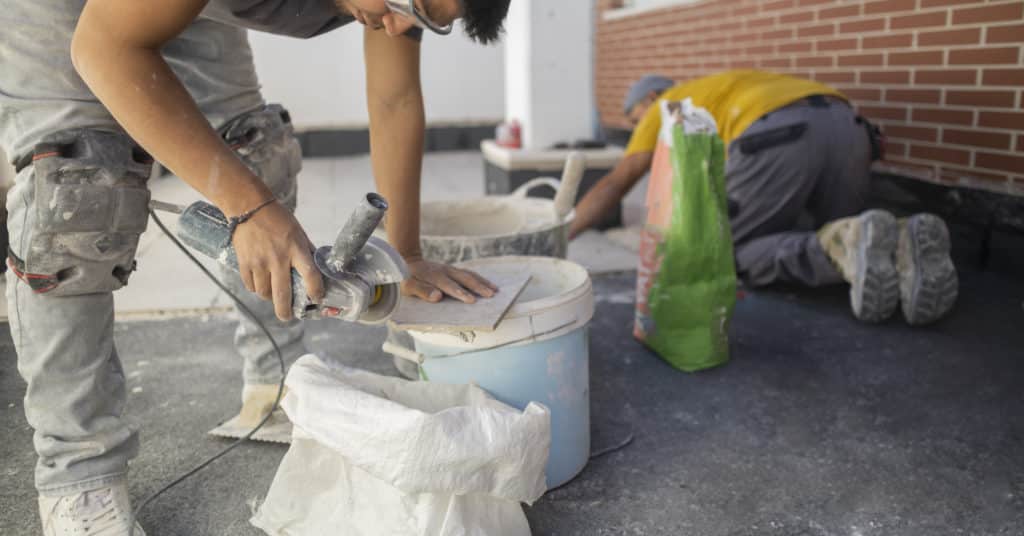 Construction workers cutting tiles outdoors