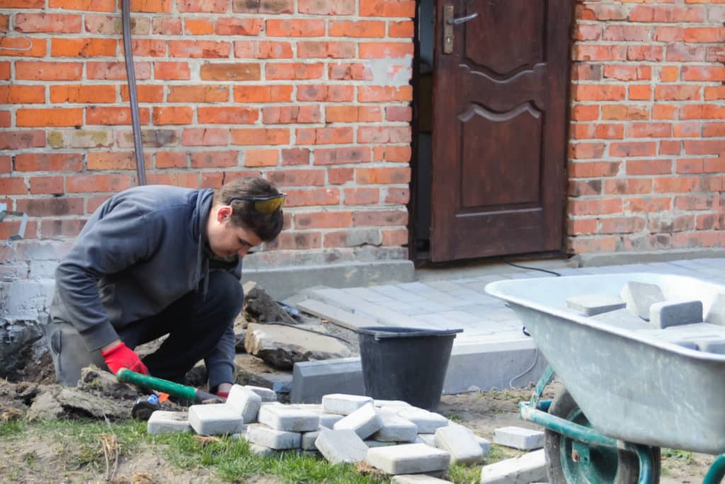 Man laying pavers for outdoor pathway.