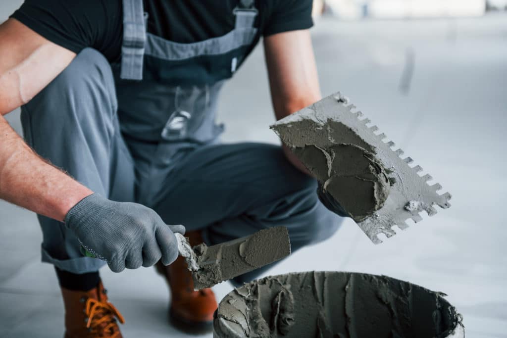 Worker applying mortar with trowel for tiling.