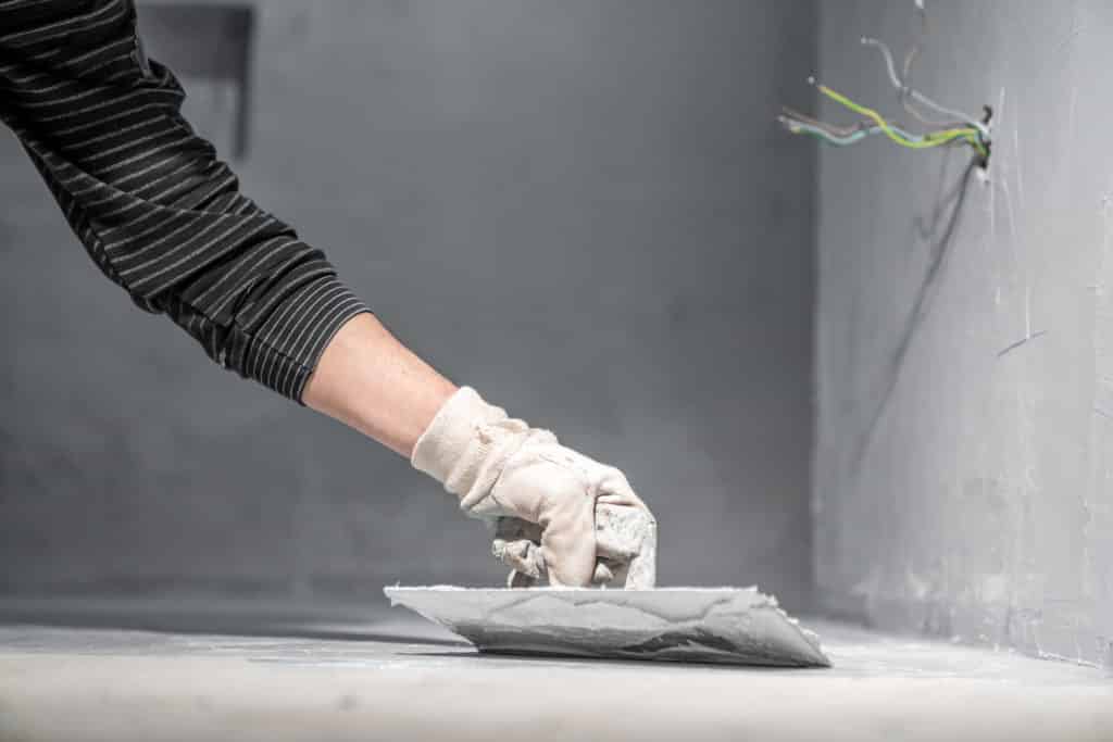 Person applying plaster to wall.