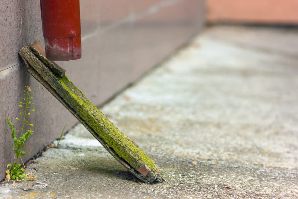 Wooden plank supporting a rusted pipe outdoors.