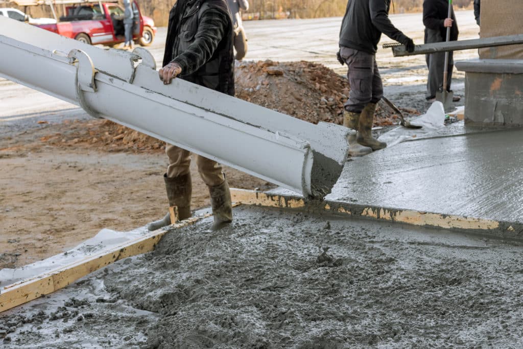 Workers pouring concrete at construction site