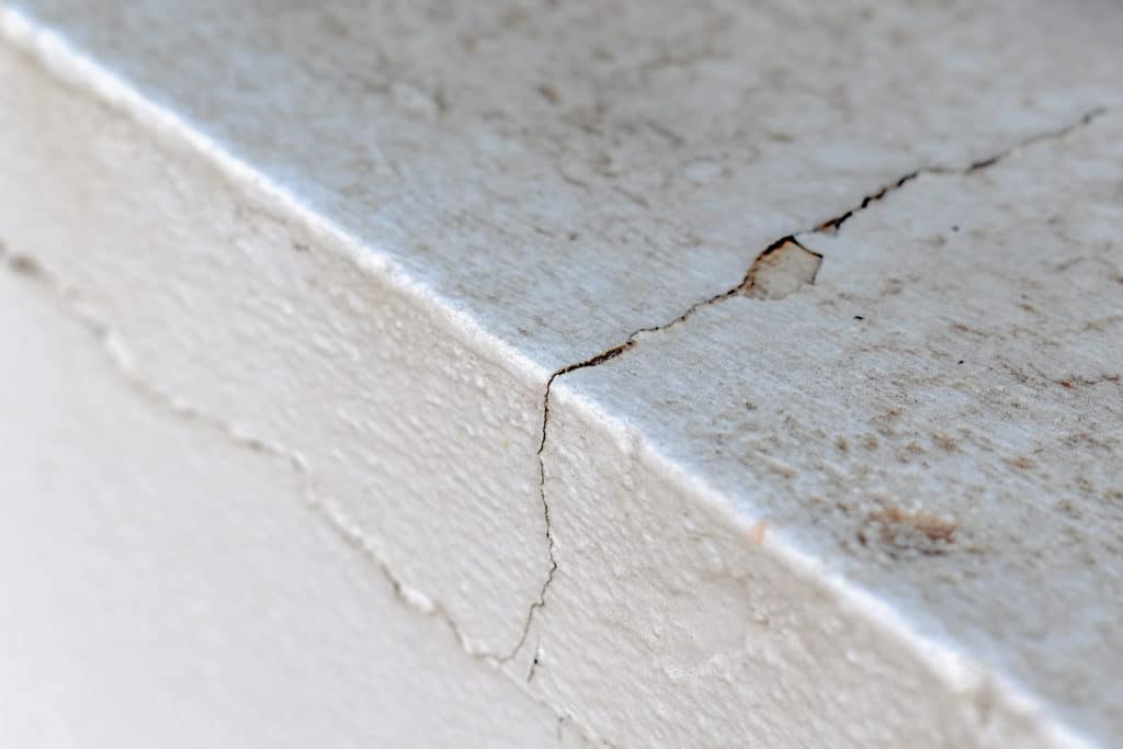 Close-up of cracked white wall corner.