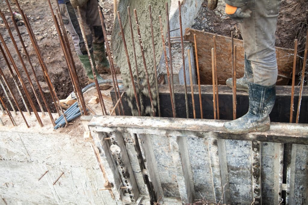 Workers at construction site with concrete and rebar.