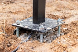 Steel column base with anchor bolts in concrete foundation.