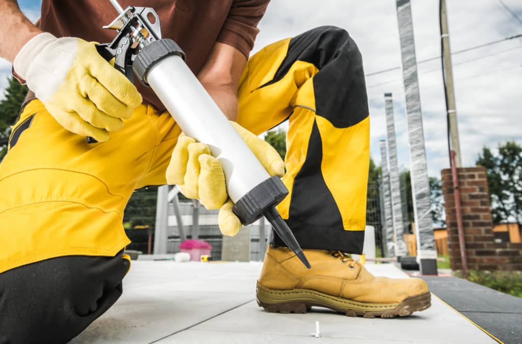 Worker applying caulk to seal surface.