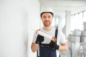 Construction worker with sealant gun at building site.
