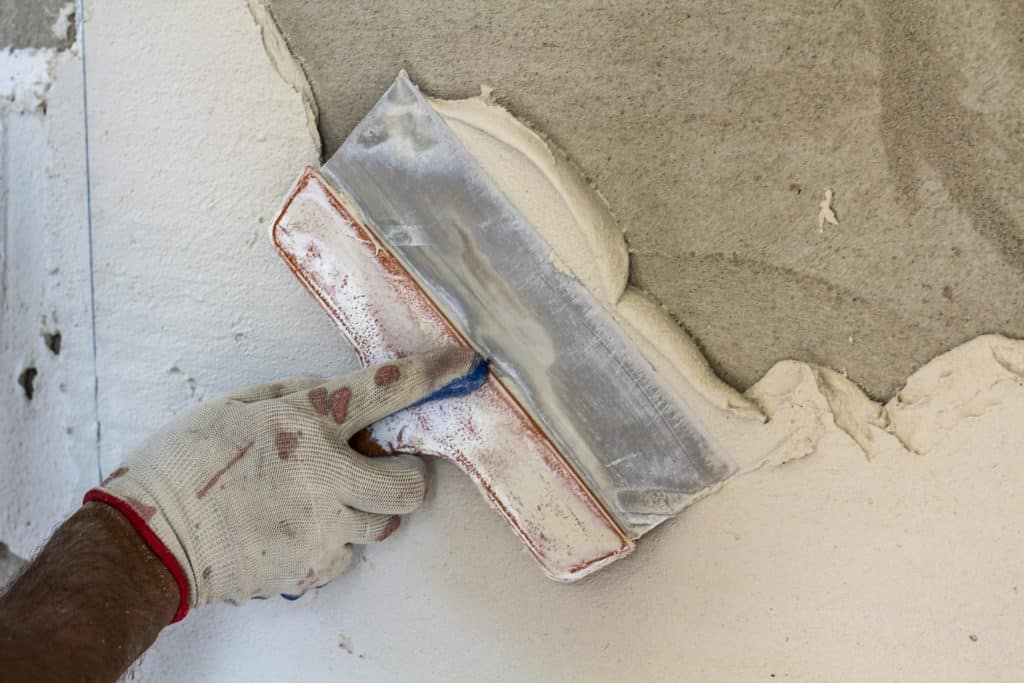 Applying plaster on wall with trowel.