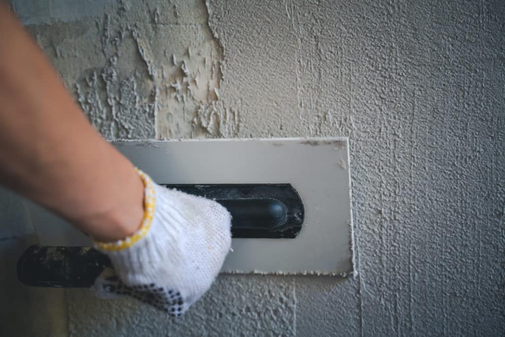 Person plastering wall around mail slot.