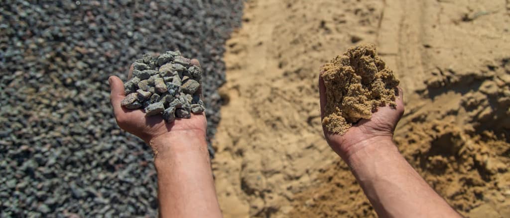 Hands holding gravel and sand, construction materials concept.