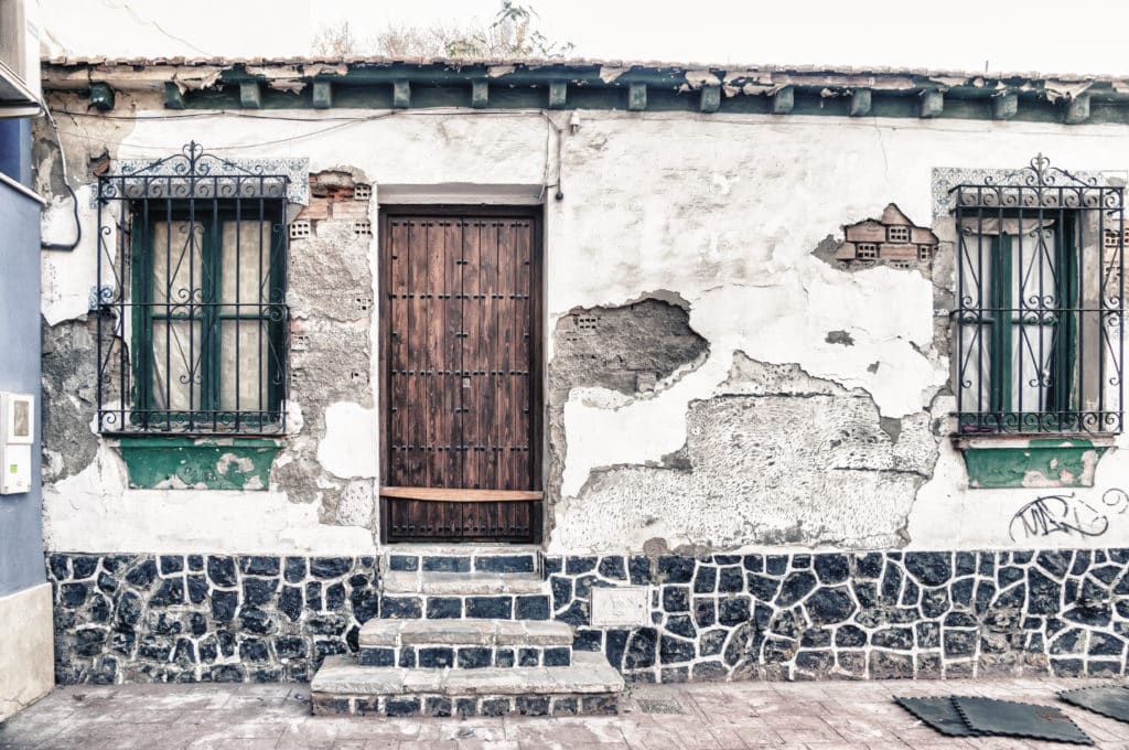 Old house with damaged plaster and wooden door.