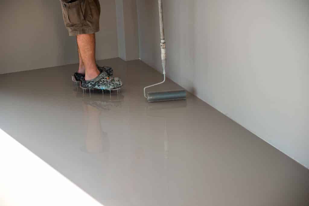 Person painting floor with a roller.