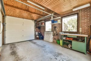 Empty garage interior with open door and workbench.