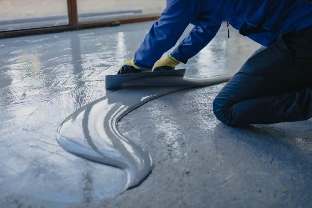 Worker applying epoxy coating to floor.